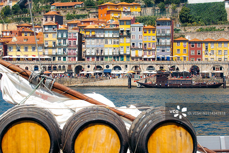 葡萄酒桶在葡萄牙波尔图的一艘船上，背景是五彩斑斓的建筑。图片素材