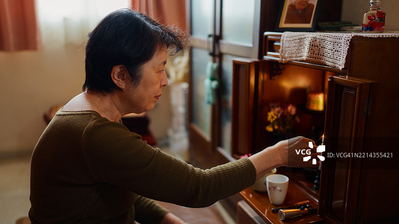 日本老年女性在家中为已故的家人和父母祈祷图片素材