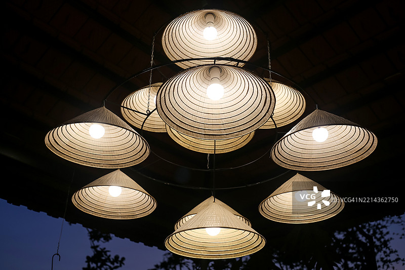 用越南斗笠制成的锥形吊灯，夜晚明亮照耀图片素材
