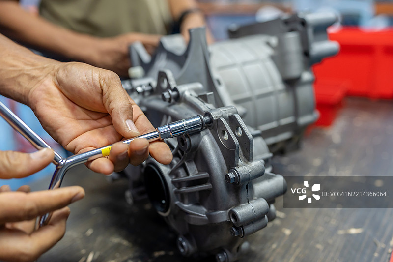 电动车工程师拆卸空气压缩机外壳，以检查内部电路板的电阻。适合电动汽车服务、混合动力车辆维护、可再生能源和现代车间创新主题。图片素材