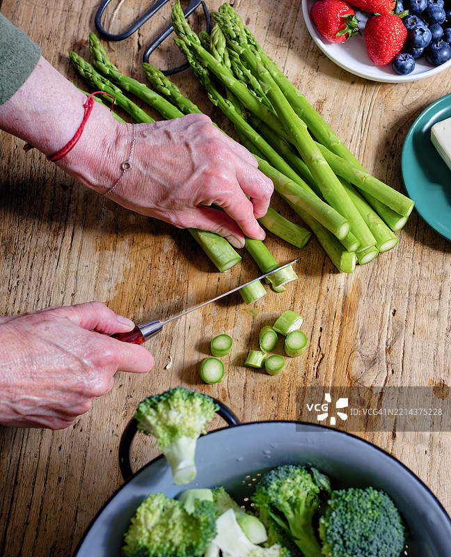 女人在乡村风格的木桌上切芦笋图片素材