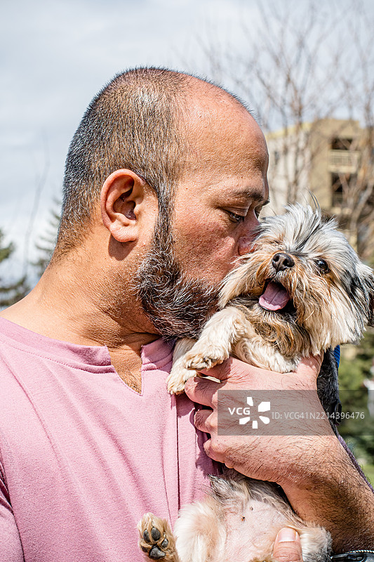 阳光明媚的春天，男人在户外拥抱狗狗图片素材
