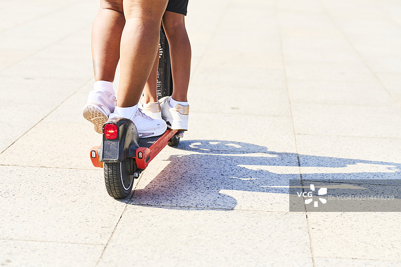 两个人在铺装道路上骑滑板车图片素材