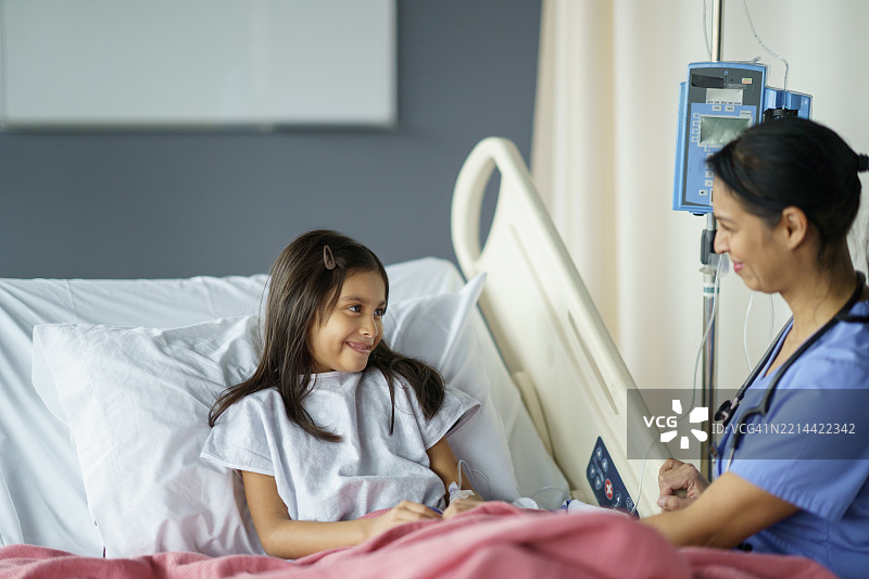 友好的护士在医院病床上为年轻女孩提供医疗护理图片素材
