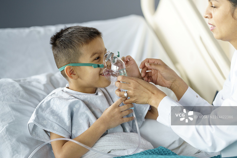 护士在病房里安慰戴着氧气面罩的生病男孩图片素材