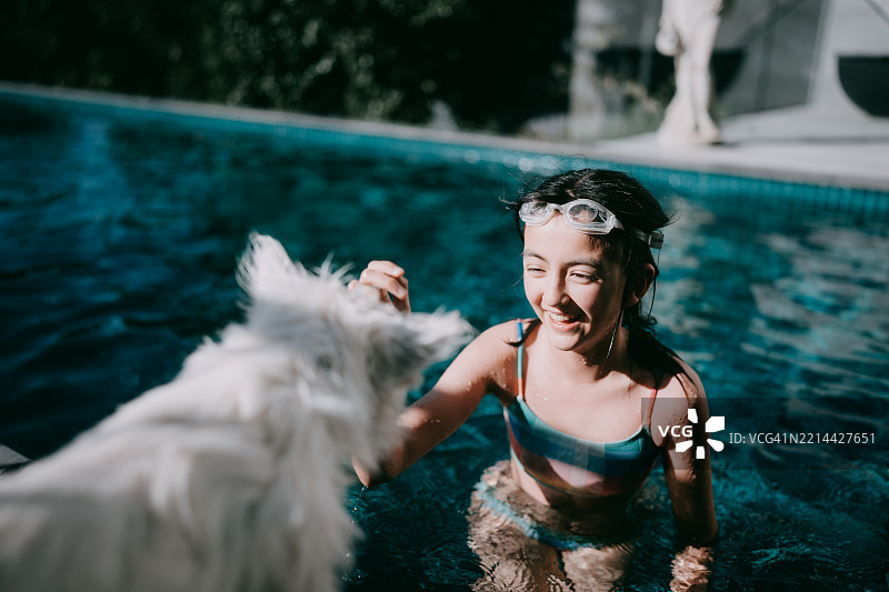 小女孩和狗在家里的游泳池旁图片素材