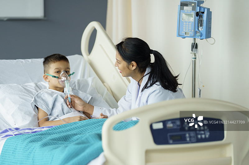 护士在病房里安慰戴着氧气面罩的生病男孩图片素材