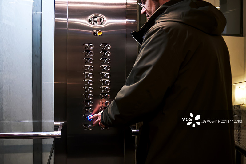 男人走下去按下电梯按钮。图片素材