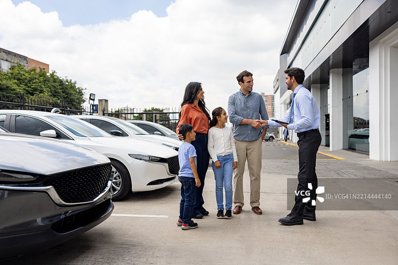 汽车销售员在展厅与一家人握手问候图片素材
