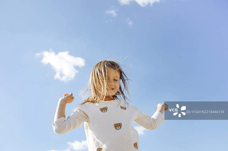 海滩假期：女孩在蓝天中与风共舞图片素材