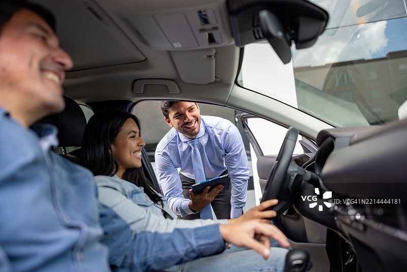 销售员在汽车经销商处向父亲和女儿展示汽车图片素材