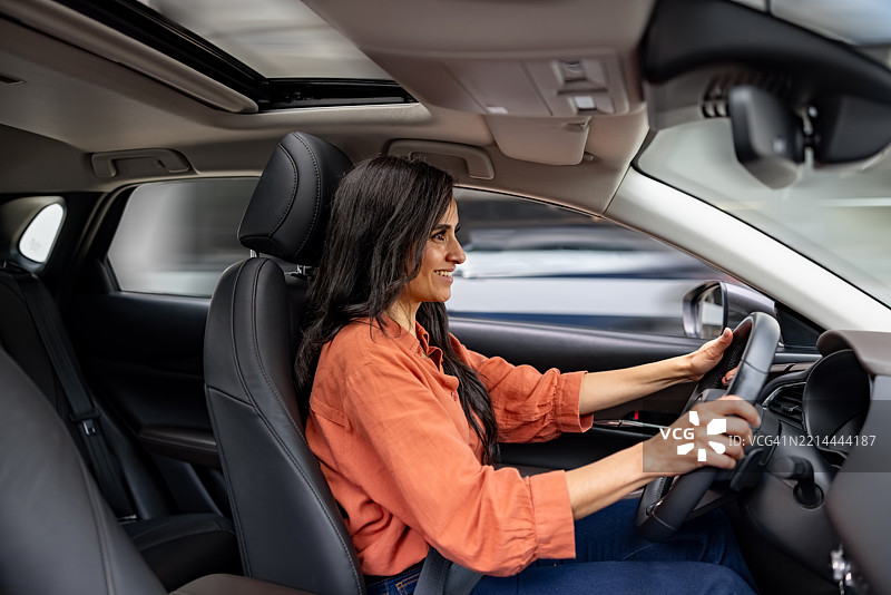 女性在汽车经销商处试驾汽车并微笑图片素材