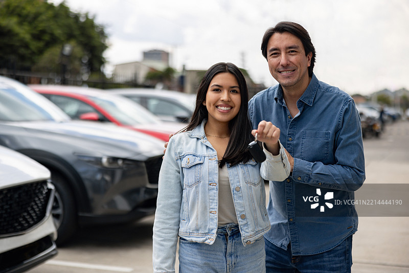 父亲和女儿微笑着手握新车钥匙的肖像图片素材