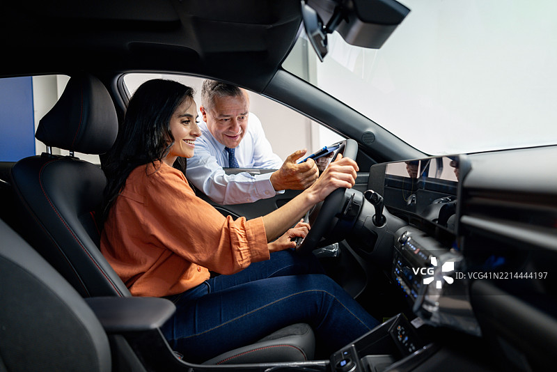 销售员在汽车经销商处向一位女性展示汽车图片素材