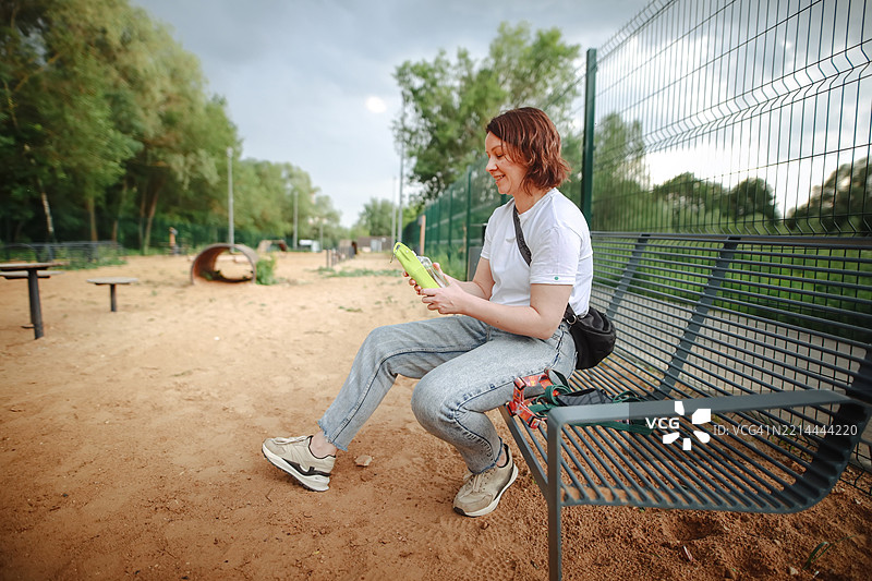 宠物护理必需品：主人在狗公园用专用瓶子提供新鲜水源图片素材