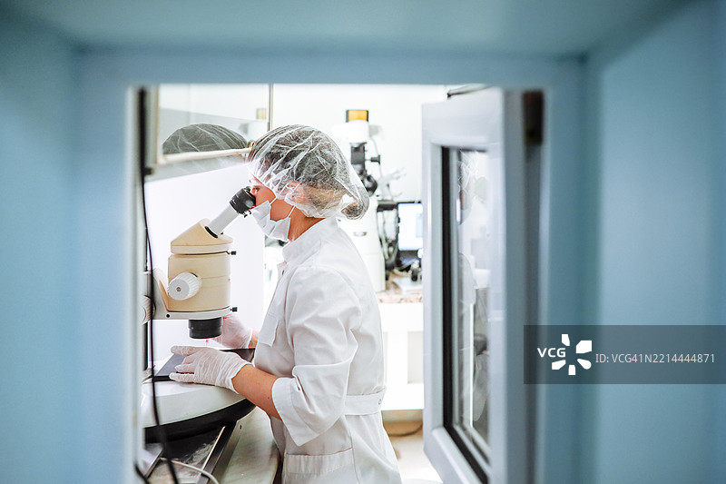 女性胚胎学家在真实实验室中使用显微镜对培养皿中的胚胎进行清洗，经过试管婴儿程序。图片素材