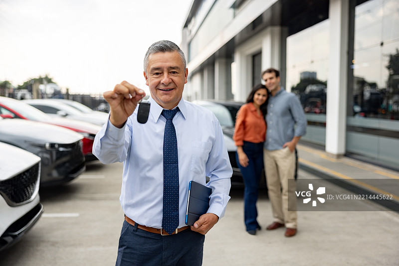 销售员在汽车经销商处手持汽车钥匙图片素材