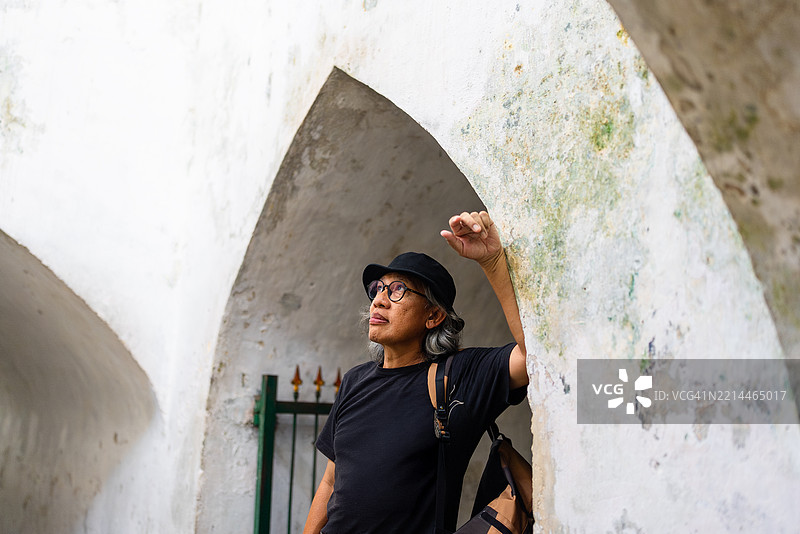 在美丽的塔曼萨里宫殿中，令人印象深刻的老年男性游客，适合雅加达的假期或夏季概念背景。图片素材