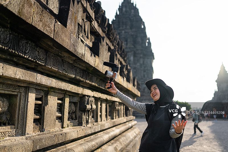 迷人的穆斯林女性在录制视频博客，一位游客在普兰巴南寺记录她的旅行经历。图片素材