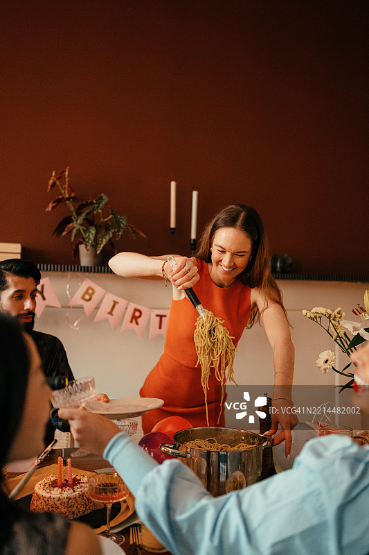 在家庭聚会上为客人端上意大利面女性图片素材