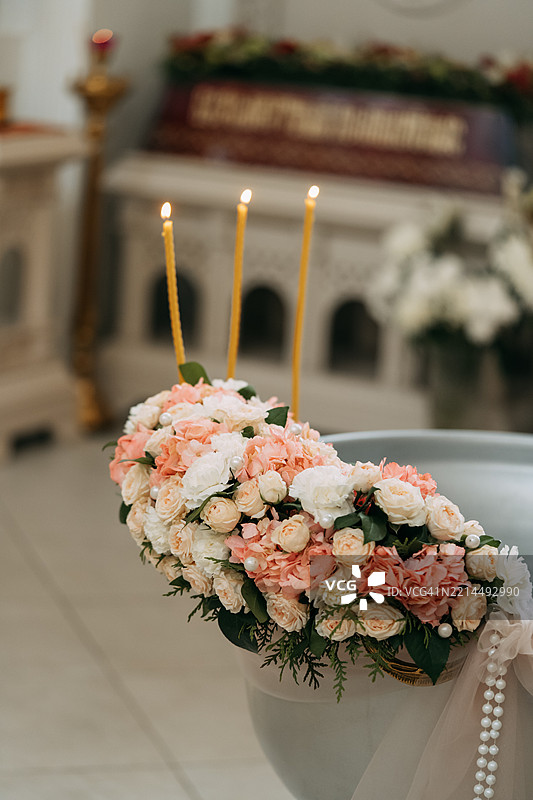 教堂内洗礼仪式上，蜡烛在花卉布置旁燃烧图片素材