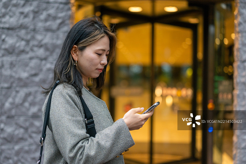 年轻女性自由职业者在城市中使用智能手机图片素材