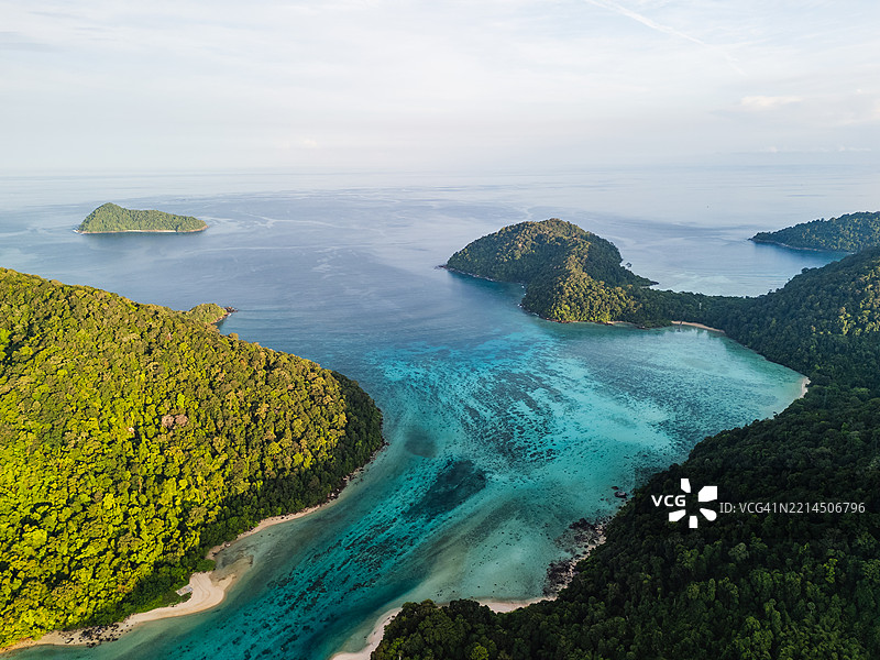 热带岛屿环绕着碧蓝泻湖的鸟瞰图，展现清澈的海水、沙滩和茂密的沿海丛林。图片素材