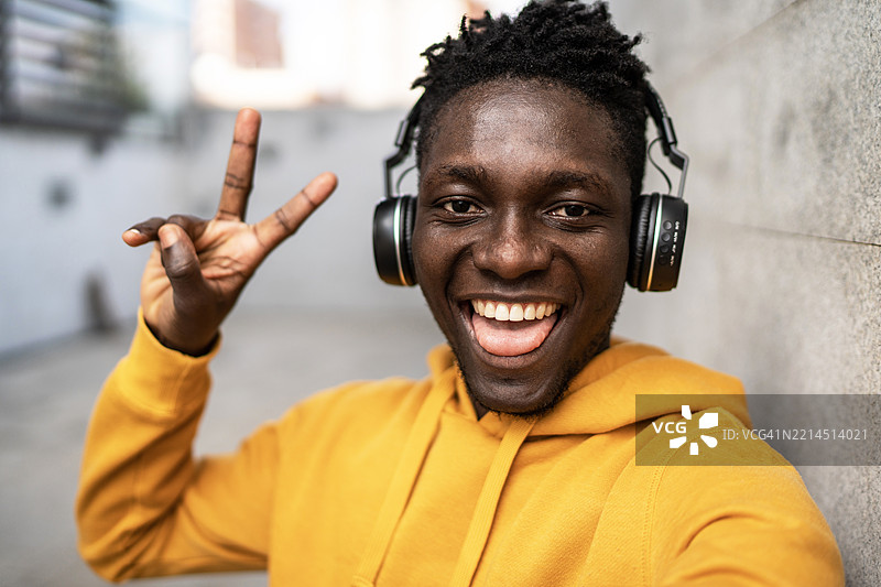 年轻男子戴着耳机听音乐并做出胜利手势图片素材