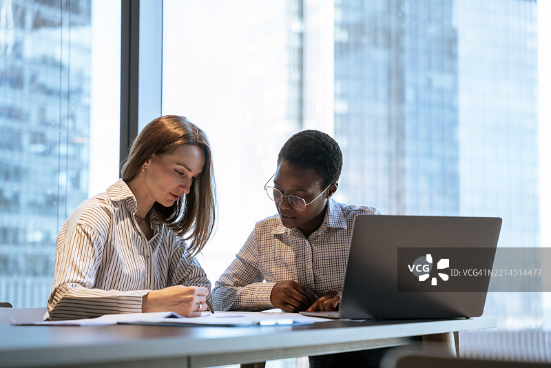 两位商务女性在现代办公室环境中讨论文件图片素材
