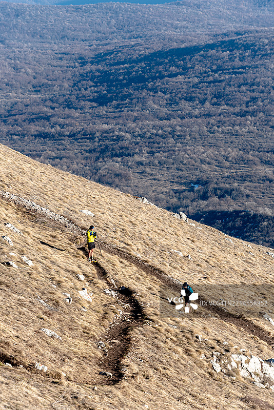 两名徒步旅行者在秋季的山间小径上行走图片素材