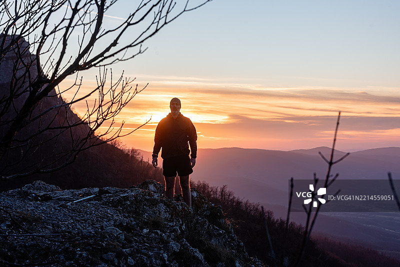 登山者在日落时分的山顶上摆姿势，庆祝徒步探险的成功图片素材
