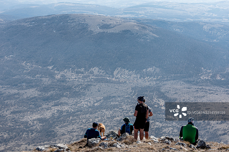 登山者与他们的狗在山顶休息，享受美丽的风景图片素材