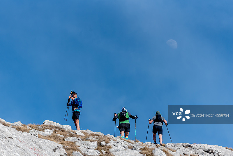 登山者在蓝天和月亮下到达山顶图片素材