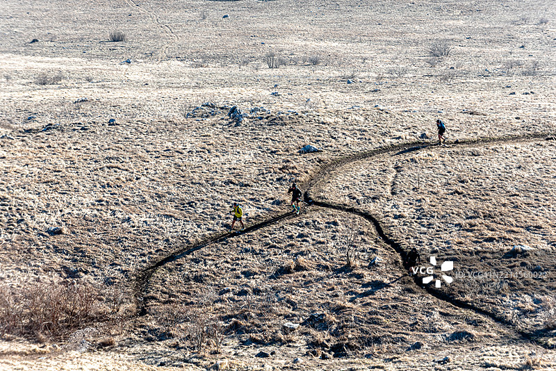 徒步旅行者在荒凉的景观中沿着蜿蜒的小路行走图片素材