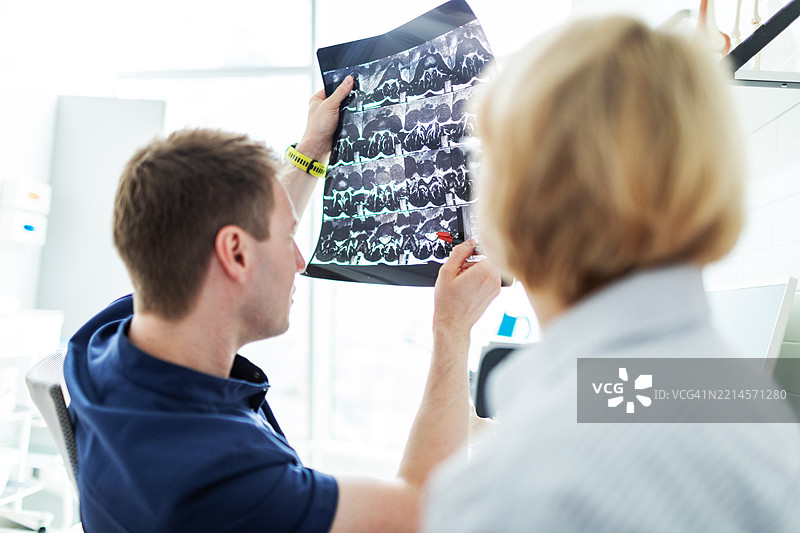 物理治疗专家向患者解释脊柱X光图像图片素材