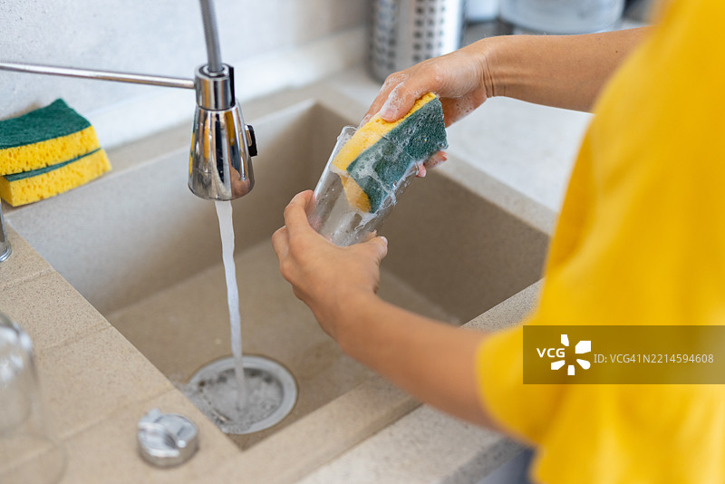 现代厨房水槽中洗涤玻璃杯的手部特写图片素材