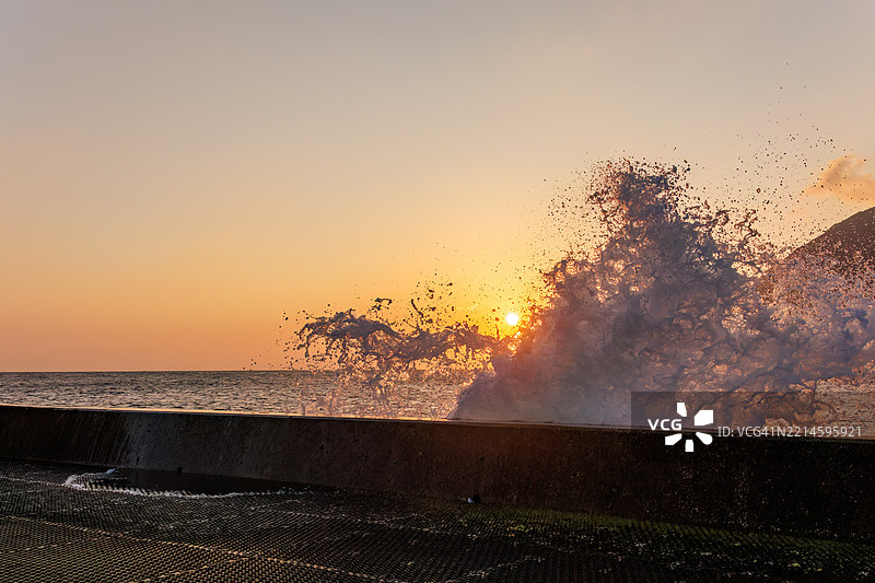 太平洋的汹涌波涛沐浴在八丈岛的晨光中。清晨时分，底港和底港海滩的日出。图片素材