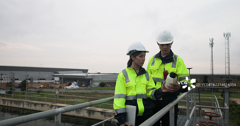 两名工业或环境工程师在笔记本电脑上讨论污水样本以进行污水处理。图片素材