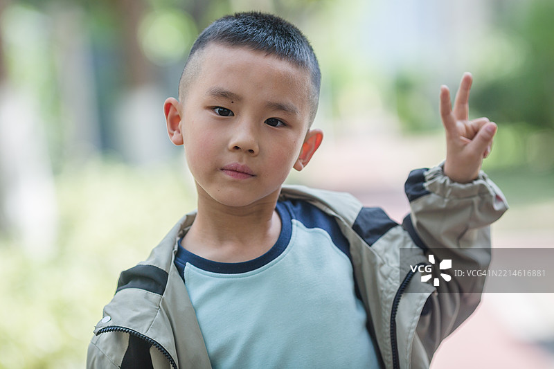 公园里做出和平手势的男孩肖像。图片素材