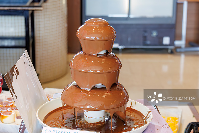 华丽的巧克力喷泉。自助餐厅。许多食物摆放在春季樱花的展示下。图片素材