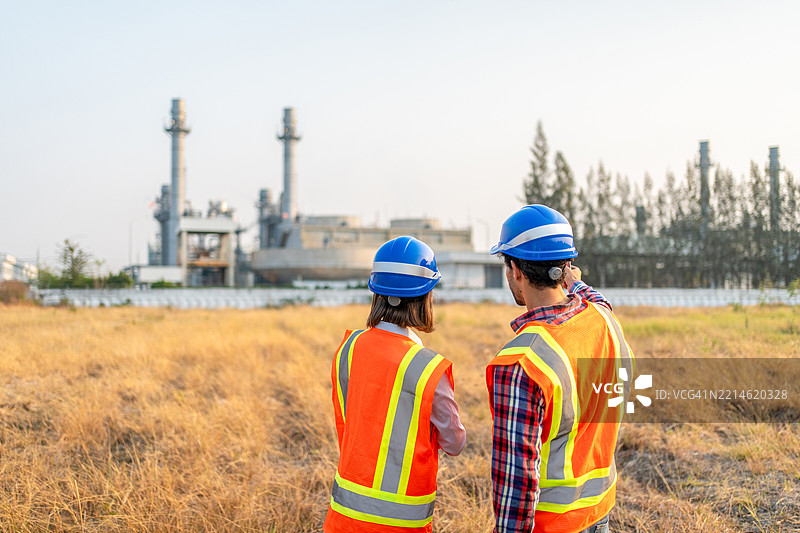 两名工程师在石油和天然气炼油厂工厂前使用笔记本电脑工作图片素材