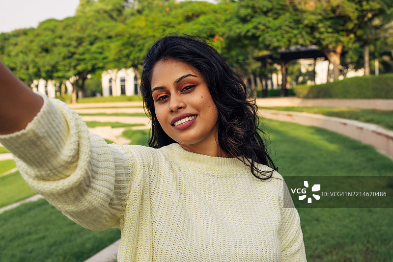 阳光明媚的日子里，微笑的女性在户外自拍图片素材
