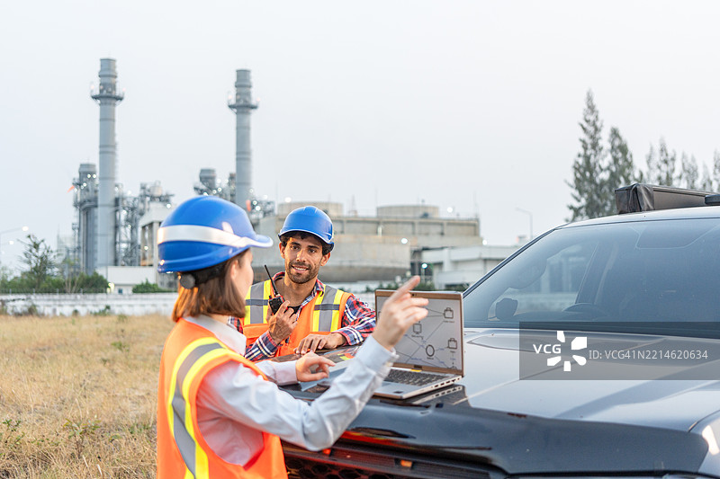 两名工程师在石油和天然气炼油厂的前方使用笔记本电脑工作图片素材