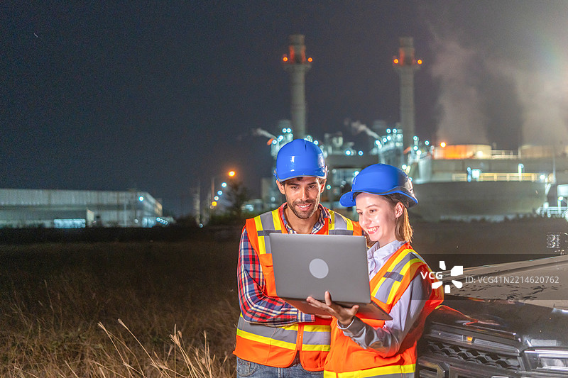 两名工程师在石油炼油厂前工作。图片素材