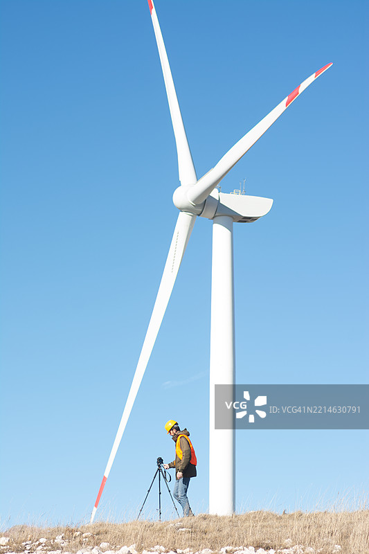 山丘上一个人在现代水平轴风力涡轮机下图片素材