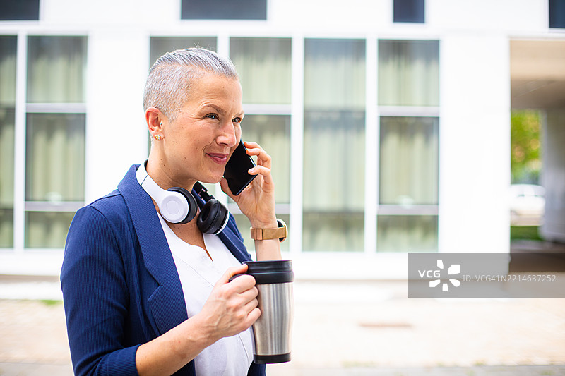 美丽的女商人走向她的办公室，并在手机上通话图片素材