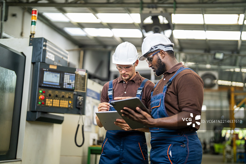 两名工厂工人在机器操作和故障排除方面合作图片素材