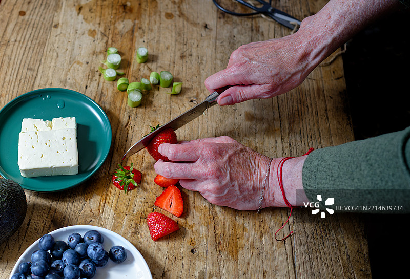 女人在乡村风格的木桌上切草莓图片素材