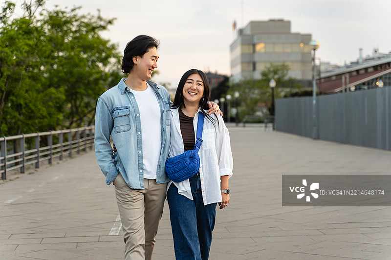 年轻的亚洲情侣在城市的人行道上漫步图片素材