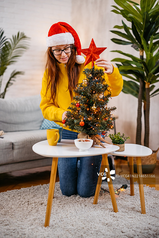 年轻女性在家中装饰圣诞树，庆祝圣诞节假期图片素材